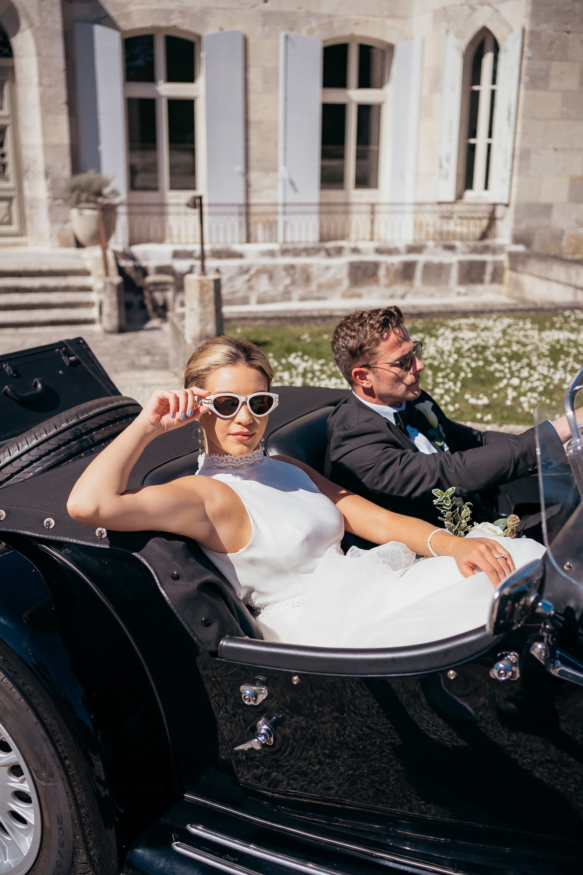 Mariés au volant de leur Morgan devant un château