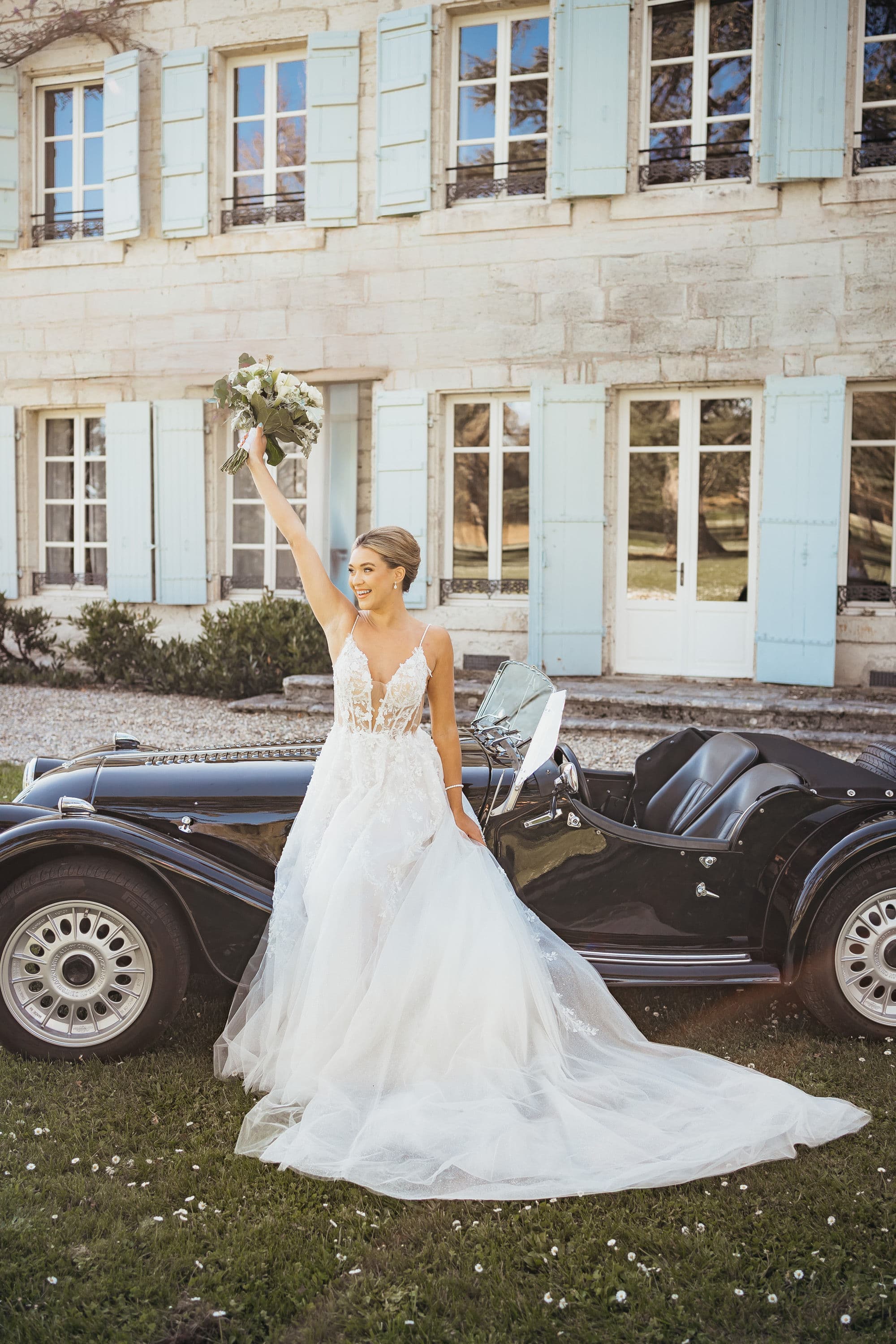 Mariée avec bouquet devant une Morgan noire